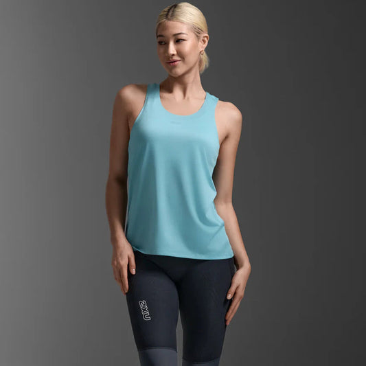 Woman wearing a light blue tank top and black leggings on a gray background